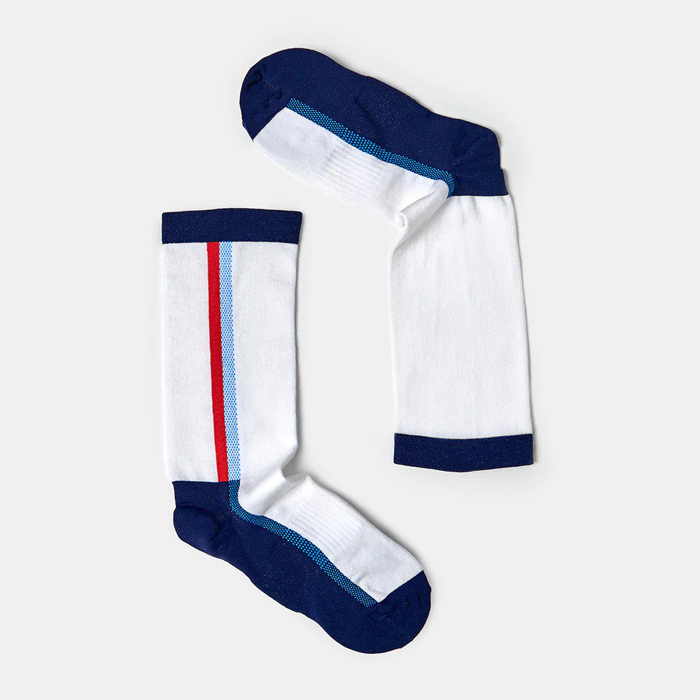 A pair of white knee-high socks with navy blue toes, heels, and cuffs. One sock has a red and light blue stripe running vertically down the side. The socks are arranged on a light gray background.