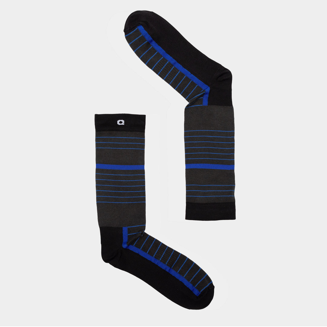 Two black socks with blue and gray horizontal stripes are arranged on a light gray background, one laid out vertically and the other horizontally to form an L shape.