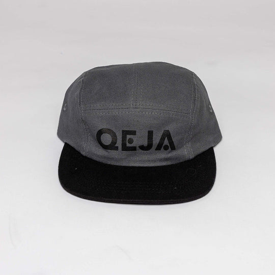 A gray and black five-panel cap with the word QEJA printed in black lettering on the front. The background is plain and white.