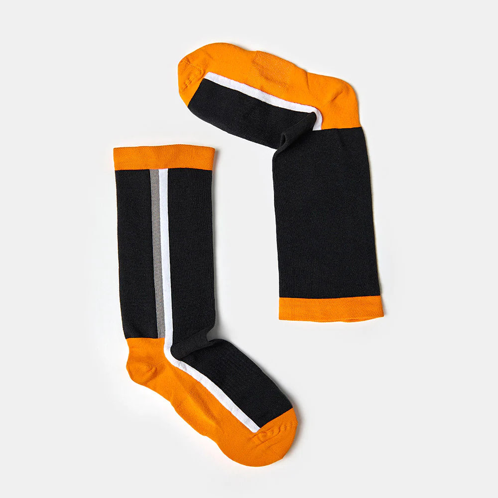 A pair of knee-high socks with black bodies, orange toes, heels, and cuffs, and a single white vertical stripe running down each sock. The socks are laid flat on a light gray background.