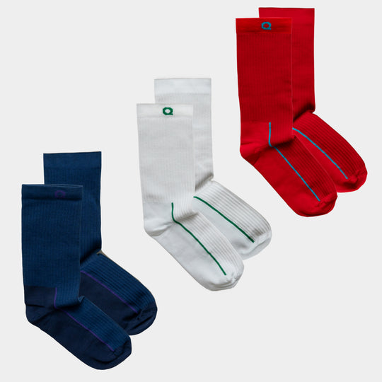 Three pairs of crew socks are displayed: one pair is navy blue with a purple stripe, one pair is white with a green stripe, and one pair is red with a blue stripe. Each pair is neatly folded and placed side by side.